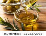 Small photo of The moment olive oil is poured into a glass bowl set against a wooden background