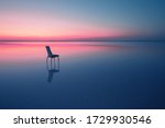 Chair among smooth water of lake at the sunset. The concept of solitude and unity with nature. A chair stands in the water of the Salt Lake Ace. Anatolia, Turkey