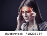Young woman is suffering from a headache against a dark background. Studio shot