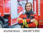 Fire fighter woman standing in front of a fire truck with her arms crossed
