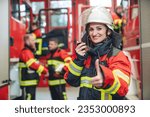 Beautiful fire fighter woman with her helmet standing in the firehouse