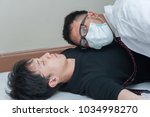 Small photo of Attractive Asian doctor listening heartbeat of young Caucasian man during performing autopsy or postmortem of death guy from overdosing pills. Concept Drug addiction and social issue teenager.