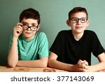 two teenager boys in myopia glasses close up portrait on blue wall background
