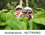  two Boy hiding in grass looking through binoculars outdoor