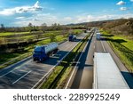 Small photo of Heavy Highway transportation scene with Convoy of white transportation trucks in one way and blue tank tracks passing in the opposite way on rural highway under a beautiful blue sky