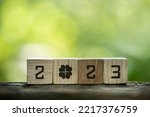 Wooden cubes with numbers 2023 on bokeh nature background.Lucky clover concept.