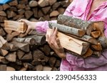 Preparing for the heating season with wood heating. Firewood in the hands of woman.