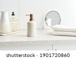 Zero waste bottle of soap and stack of clean cotton towels placed on cupboard near vase and mirror in bathroom