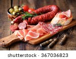 Cured meat platter of traditional Spanish tapas - chorizo, salsichon, jamon serrano, lomo - erved on wooden board with olives and bread