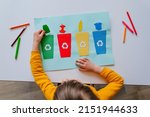 Little girl playing with poster of garbage containers for sorting at kindergarten or primary school. Recycling education concept.