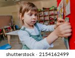 Small photo of Little girl learning days of week at kindergarten. Didactic materials on the velcro board using for preschool education. Selective focus.