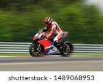 Motorcycle rider in a white helmet and gear racing at high speed on race track with motion blur. Sports theme racing
