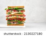 Big tasty sandwich with ham, salami, salad, cheese and tomatoes on white background