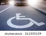 Handicap symbol on road, traffic and pedestrians in background