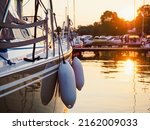 sunset view on sailing yacht moored on jetty in the port, close up view on sailboat hull, bow and fenders