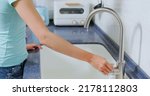 Small photo of close up of leaking faucet in kitchen - asian woman hand turn off water dripping from tap