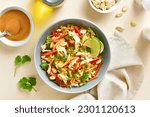 Small photo of Crunchy thai style chicken salad in bowl over light stone background. Top view, flat lay