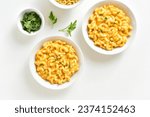 Small photo of Macaroni and cheese in bowl over white background. Top view, flat lay