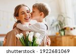tender son kisses the happy mother and gives her a bouquet of tulips, congratulating her on mother