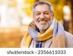 Small photo of Portrait of happy positive mature man with broad smile in elegant clothes on an autumn walk in city park