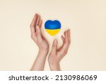 Heart with print the national flag of ukraine in female hands. Flat lay.