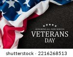 Closeup of American flag with Text Veterans Day Honoring All Who Served on black textured background.