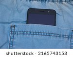 Smartphone in the pocket of denim pants, close up, denim background with copy space.