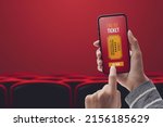 Woman holding a smartphone and buying movie tickets online using a mobile app, cinema hall and seats in the background, POV shot
