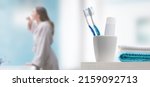 Small photo of Young woman brushing teeth in the bathroom, toothbrushes and toothpaste in the foreground