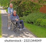 Small photo of Knutsford, Cheshire, UK. 2nd June 2023. Customer with attendant in self propelled wheelchair hired from the Red Cross Mobility Aids Service, Knutsford, Cheshire, UK