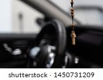 Wooden Christian rosary with crucifix hanging on car rear mirror.