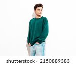 Portrait of handsome confident stylish hipster lambersexual model.Man dressed in green sweater and jeans. Fashion male posing in studio near white wall. Isolated