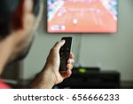 Man using remote control to switch channels. Close up hand holding apple tv remote