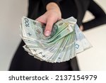Small photo of close up of several banknotes denomination of 100 zlotys Polish money zlotys holding a fan in the form of a woman in a suit. The concept of zlotys in women's hands