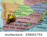 Close-up of a gold nugget on top of an old map of South Africa
