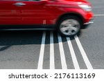 Rumble strips or speed breakers  on asphalt road surface and red car crossing them in motion blur. Traffic calming concept. 