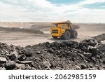 Small photo of Large quarry dump truck. Big yellow mining truck at work site. Loading coal into body truck. Production useful minerals. Mining truck mining machinery to transport coal from open-pit production