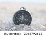 Small photo of Classic navigation compass on beach as symbol of tourism with compass, travel with compass and outdoor activities with compass