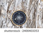 Small photo of round compass on natural wooden background as symbol of tourism with compass, travel with compass and outdoor activities with compass