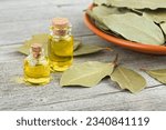 Glass bottles of essential bay laurel oil with laurel leaves on wooden rustic background. Healthy spa therapy.