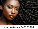 Extreme close up beauty portrait of young african woman showing long braided hair next to face.