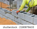 A mason is in the process of mounting a wall of aerated concrete blocks using masonry techniques on construction site
