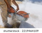 Small photo of Construction worker cutting concrete paving stabs for sidewalk using cut off diamond bladed saw.