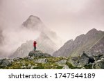 Hiker with camera standing on top of a mountain and enjoying landscape. High Tatras mountains. Landscape photographer photographs a mountain view.