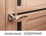 Small photo of Brown wooden interior door with emphasis on metal handle. Close up of door handle on interior door with frosted glass inserts. Interior details or catalog for furniture store.