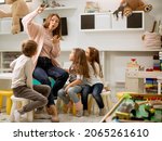 Nursery teacher talking story to group of children sitting on a small chairs at kindergarten