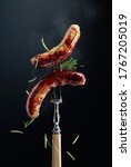 Small photo of Hot Bavarian sausages with rosemary. Sausages on a fork sprinkled with rosemary.