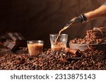 Small photo of Irish cream and coffee liquor is poured from a bottle into a glass. Coffee beans, cinnamon, anise, and pieces of bitter chocolate are scattered on the table.