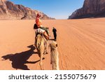 beautiful young woman tourist in white dress riding on camel in wadi rum desert, Jordan