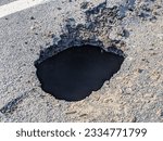 Small photo of Deep sink hole opened up in a tarmac road surface.